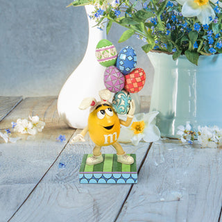 Jim Shore M&M'S: Yellow Easter M&M With Stacked Eggs Figurine sparkle-castle