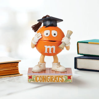 Jim Shore M&M'S: Orange M&M in Graduation Cap Figurine sparkle-castle